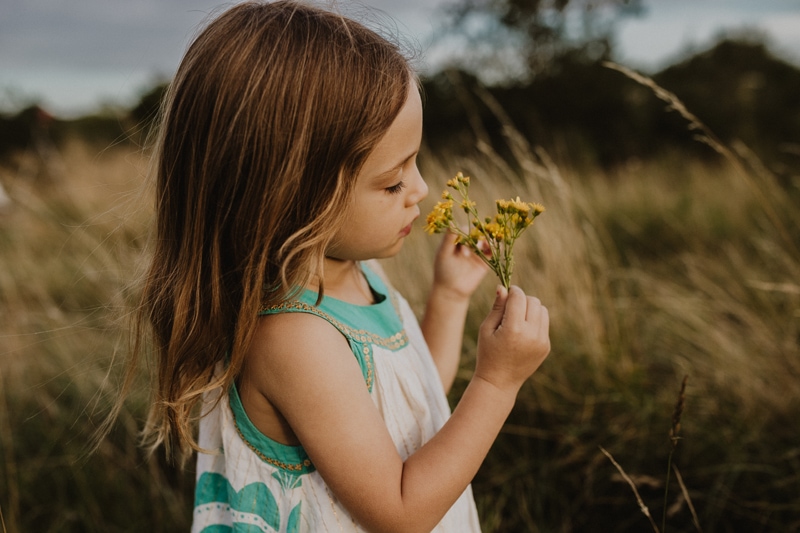 Family Photographer, young girl playing with a handful of wildflowers
