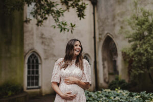 Maternity Photoshoot in St Dunstan in the East Church. Woman laughing and holding her baby bump in old church ruins in central London.