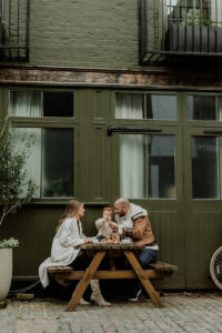 Family Photoshoot in St Luke's Mews, Notting Hill during winter. The Family is having their breakfast, coffee and croissant, sitting on a table.